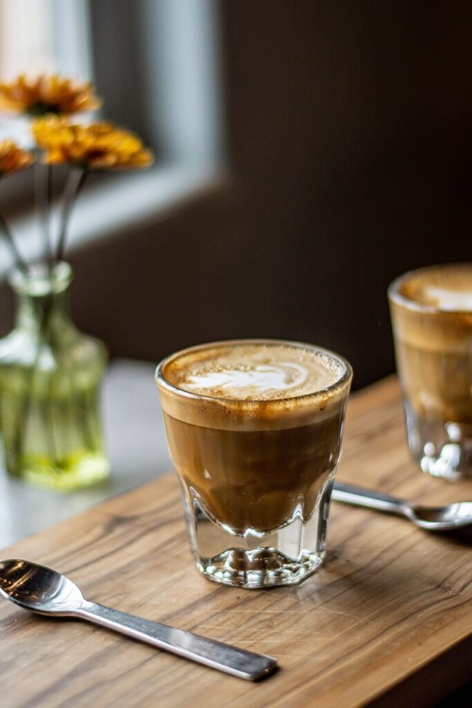 a glass of brown liquid with a spoon on a wooden table